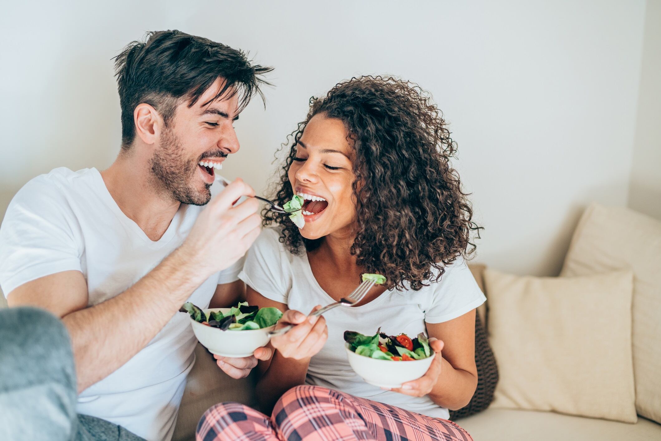 Happy man feeding his girlfriend with salad
