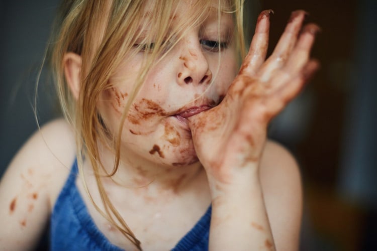 Girl snacking chocolate on face