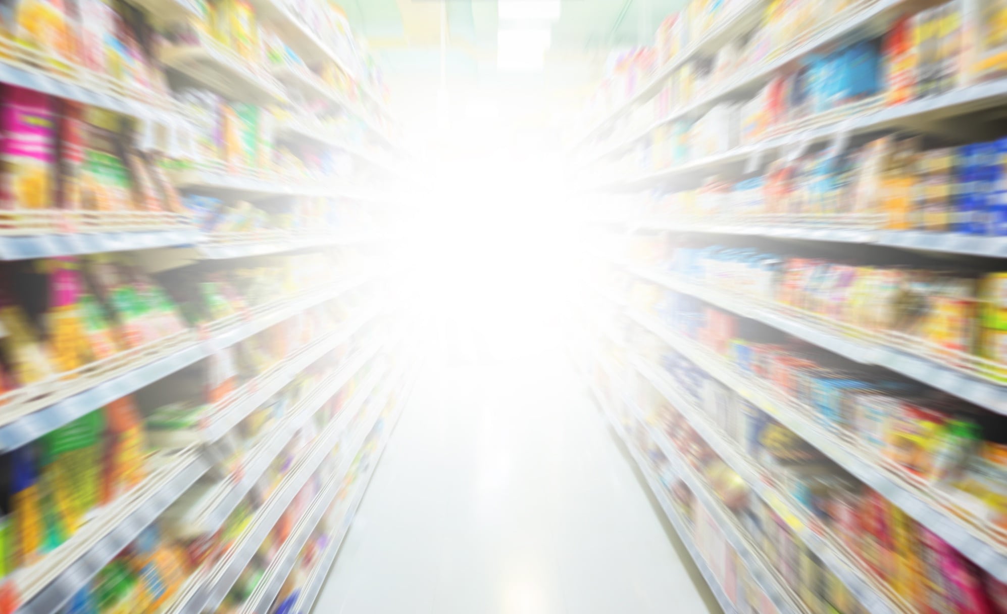 Blurred image of supermarket aisle with bright light at the end.