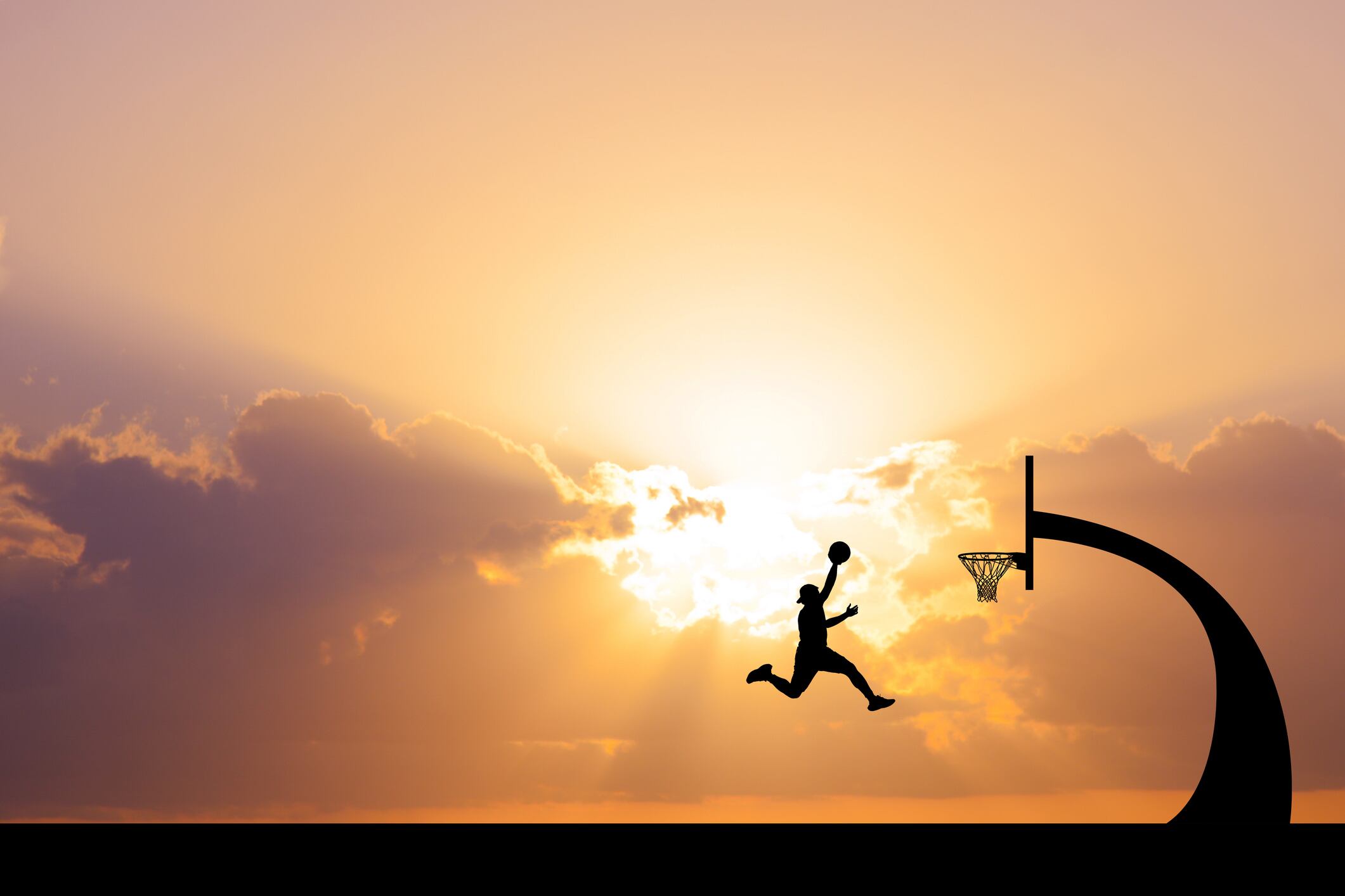 A dynamic silhouette of a basketball player mid-air, aiming for a dunk, with a stunning sunset backdrop.