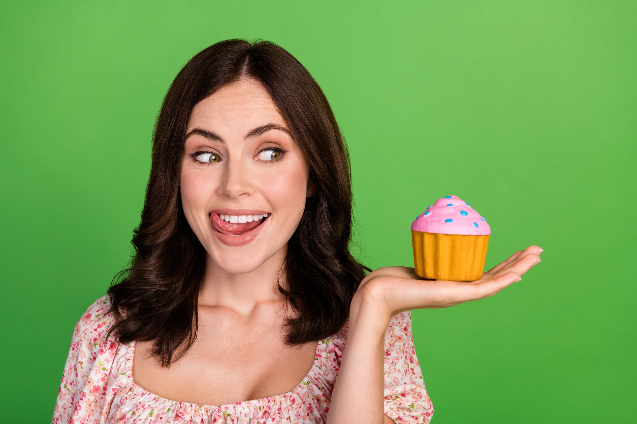 Closeup photo of young adorable pretty nice student woman wear pink top interested her baked cake muffin tongue teeth delicious isolated on green color background.