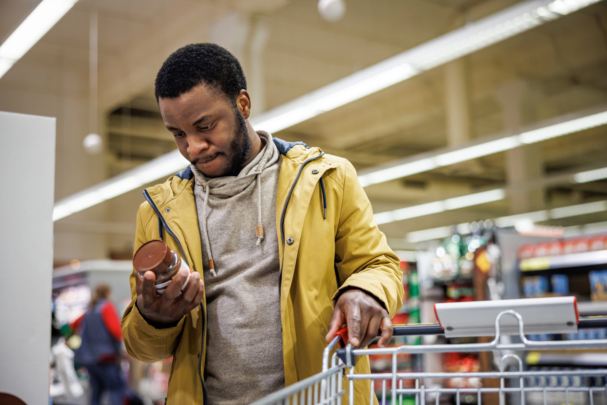 Cocoa shortage crisis tackled. Image: Young man reads nutrition labels in product in supermarket