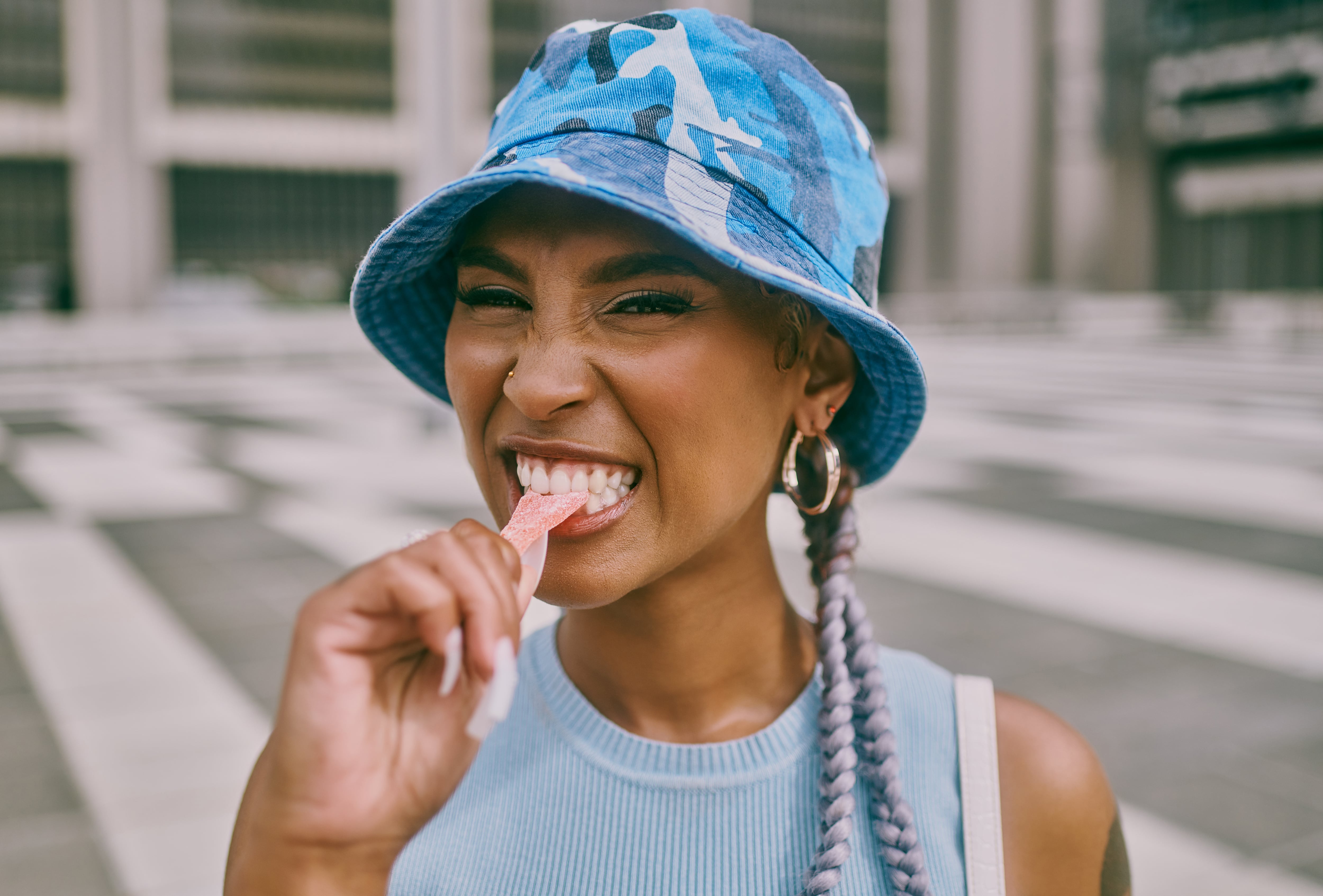 Portrait of a young woman eating candy against a city background