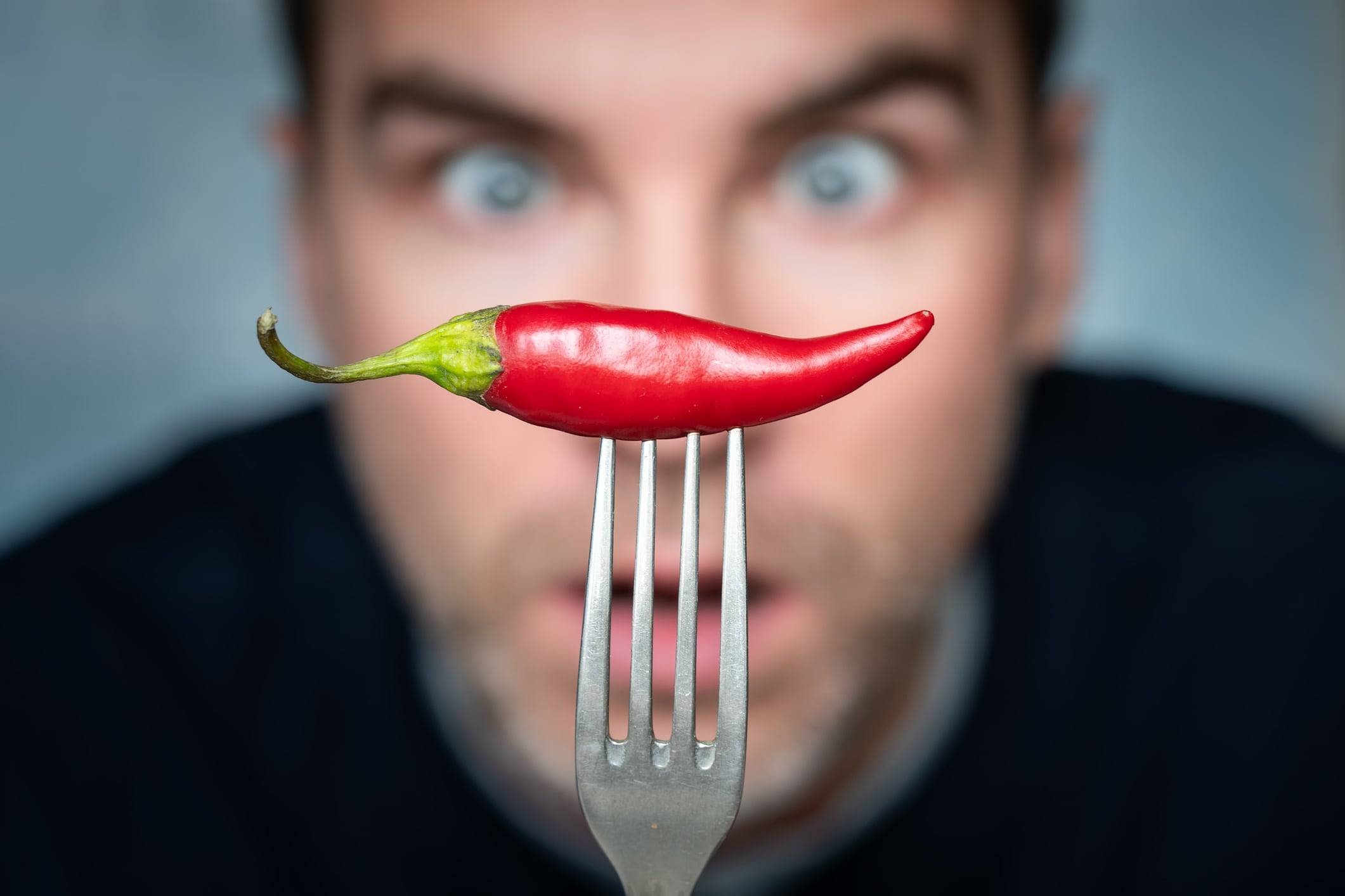 Man staring at a chilli on a fork