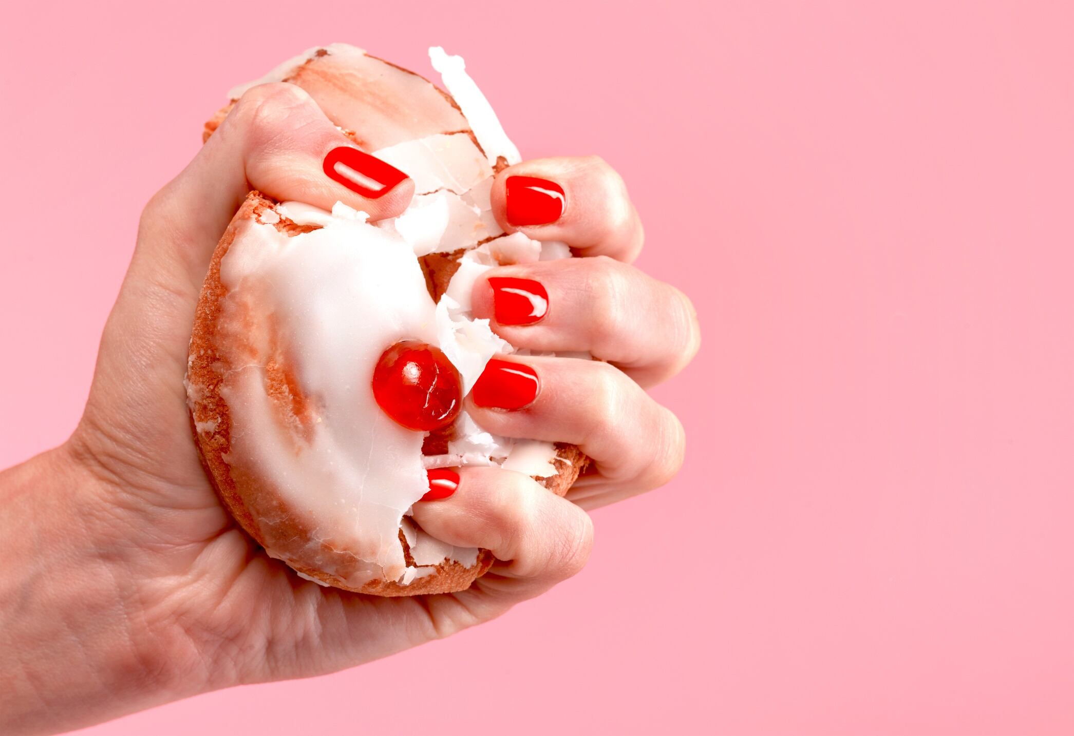 Hand crushing a red pastry
