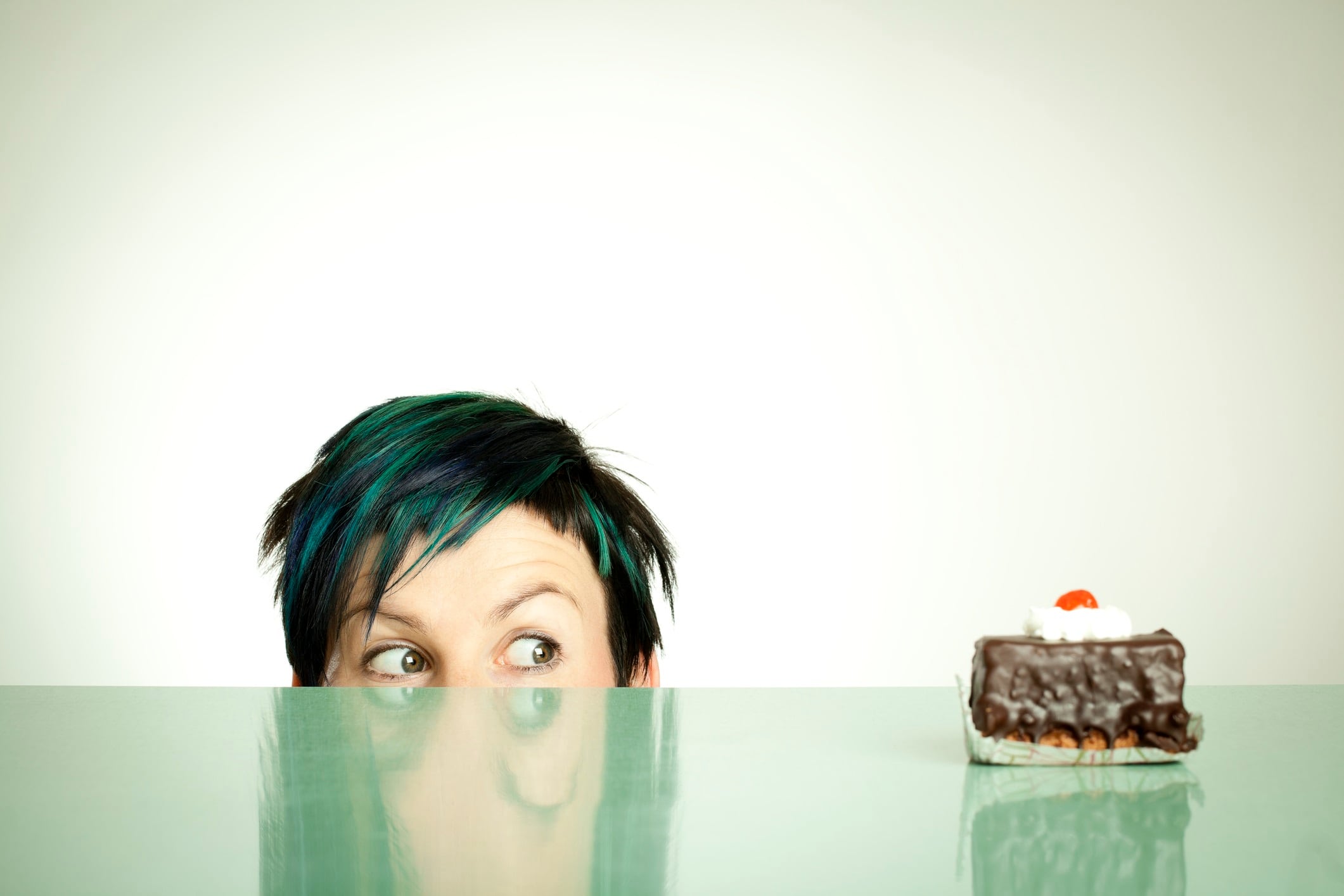 Woman with green hair looking at slice of cake.