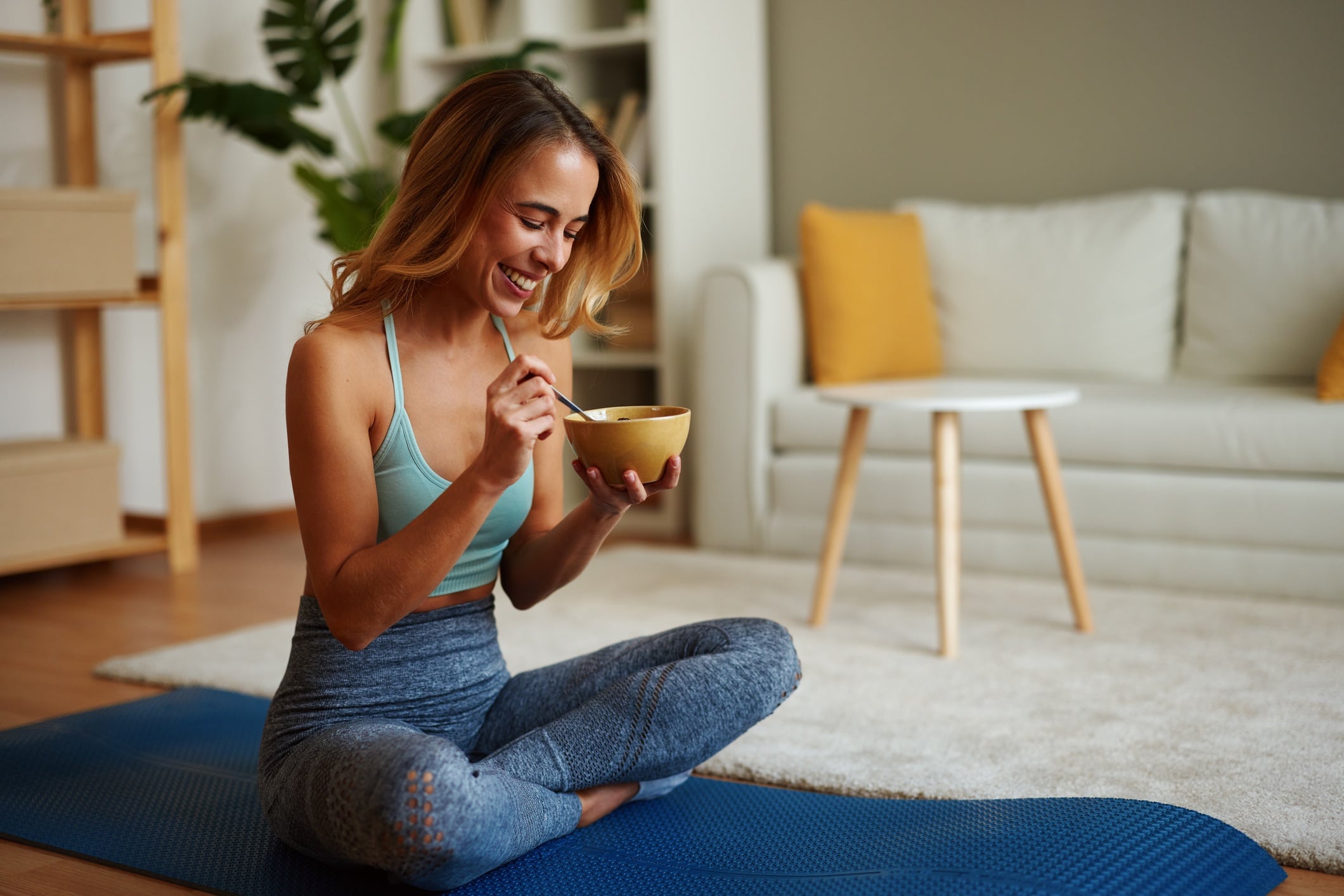 Smiling sportswoman enjoying healthy breakfast after training at home.