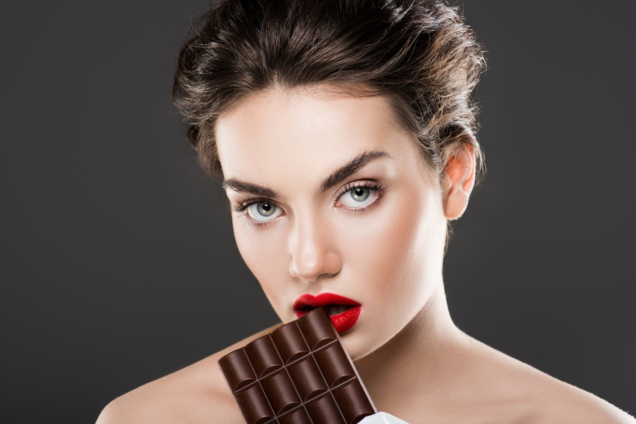 Woman holding chocolate bar, isolated on grey
