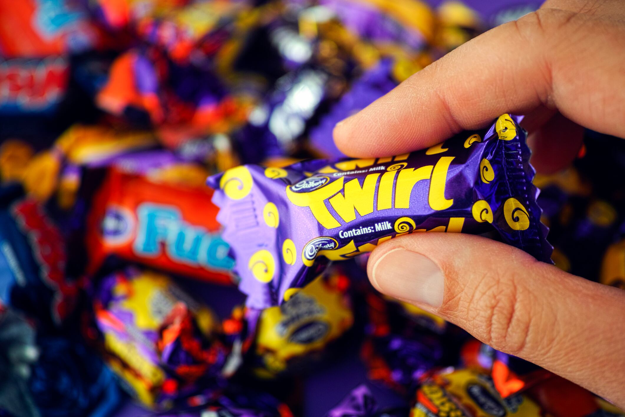 Paphos, Cyprus - November 27, 2015: Cadbury Twirl candy in womans hand with background of Cadbury candies.