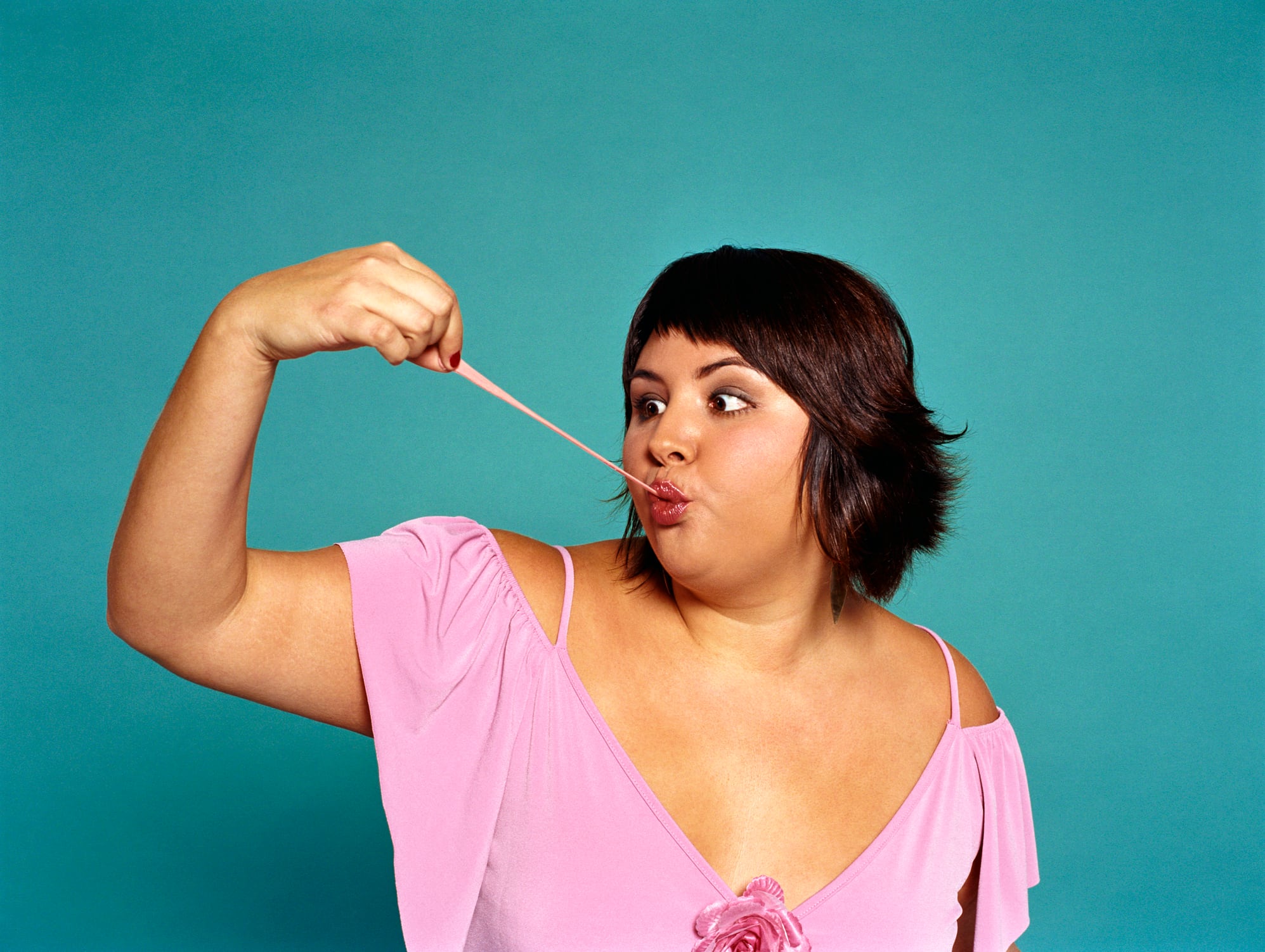 Plus-sized woman pulling chewing gum from mouth