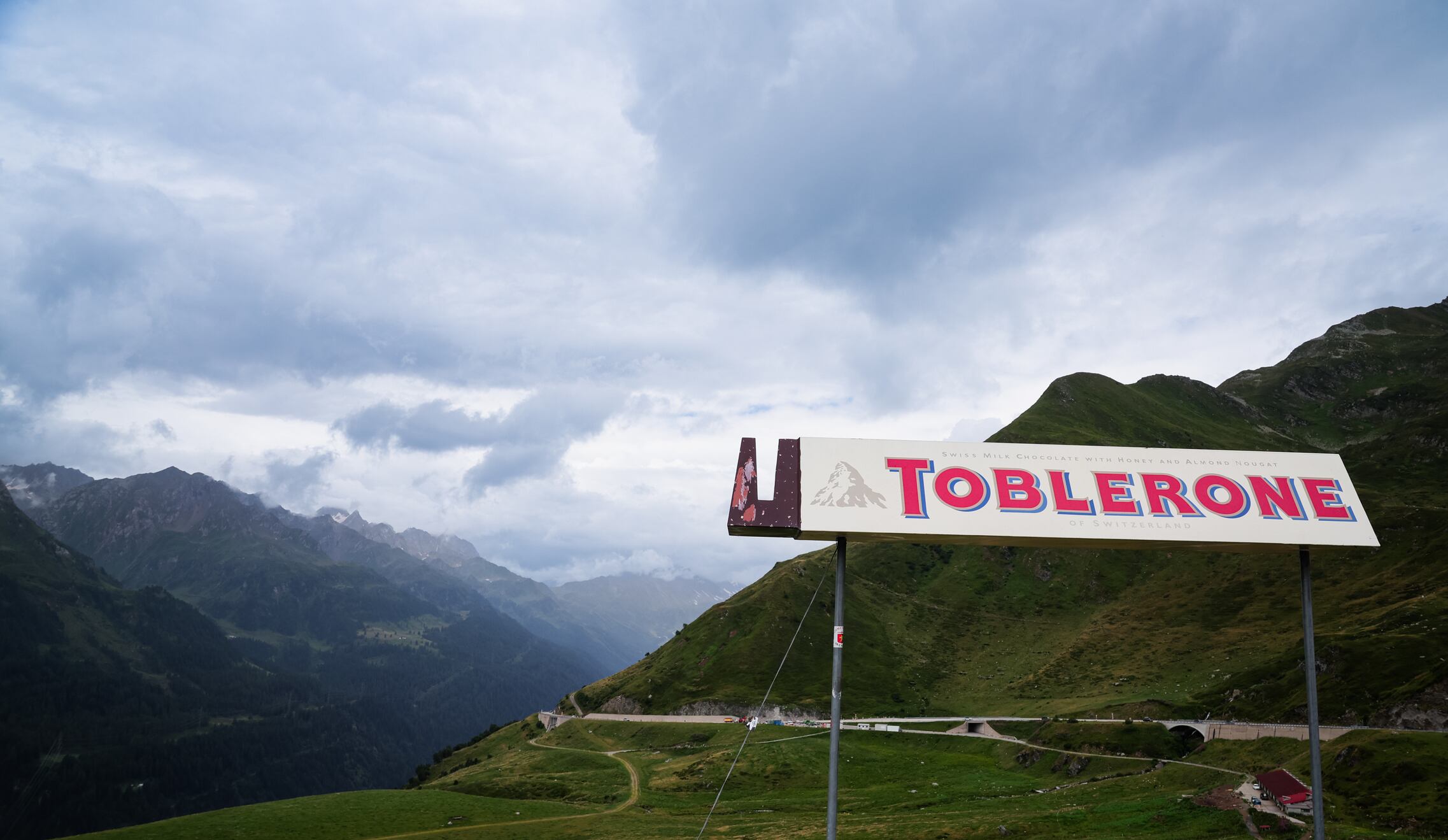 San Gottardo, Switzerland  - September 15, 2024: The Toblerone sign stands proudly amidst majestic mountain peaks in San Gottardo, Switzerland, under a cloudy sky.