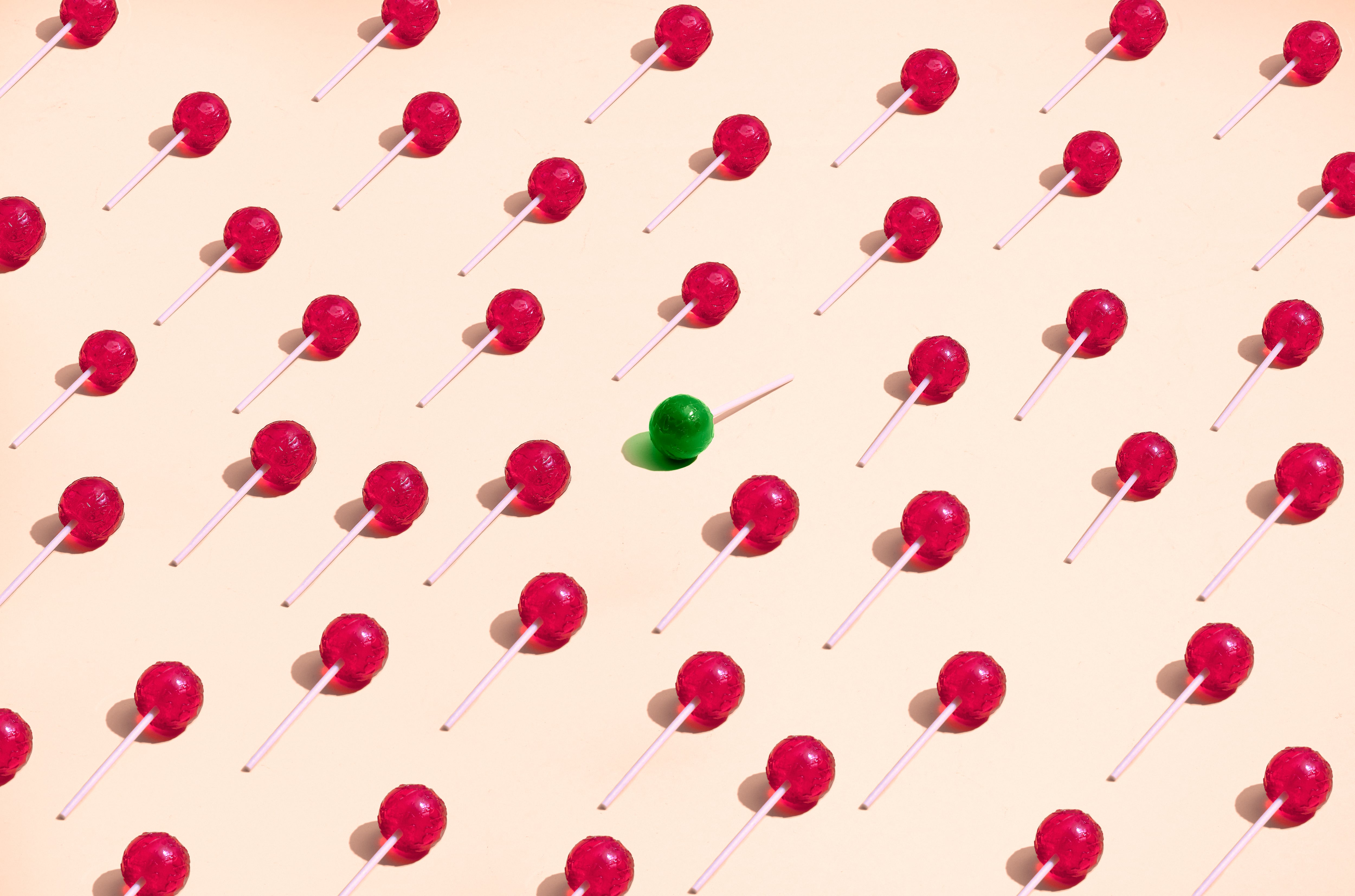 A grid of red lollies with one green lolly facing the other way to demonstrate how confectioners can hit the right trends in 2025